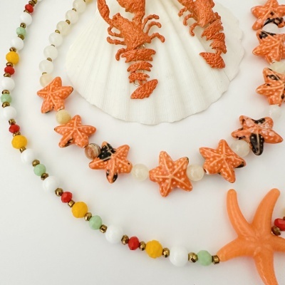 Colar colorido com estrelas do mar e acessórios em tons de laranja sobre fundo branco