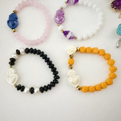 Pulseiras coloridas com contas e detalhes dourados sobre fundo branco.