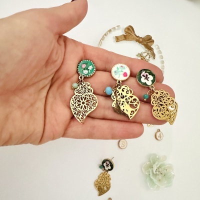 Brincos dourados com flores e pérolas em fundo branco