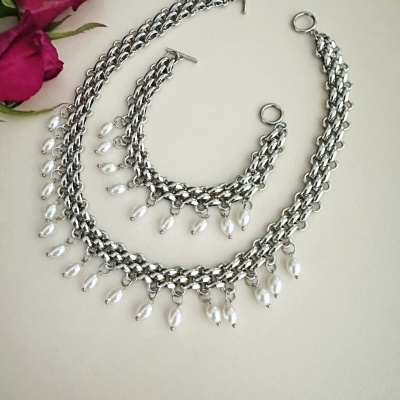 Colar e pulseira prateados com pérolas penduradas e flores cor-de-rosa