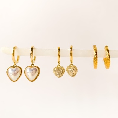 Três pares de brincos dourados, incluindo corações em pérola, corações texturizados e argolas.