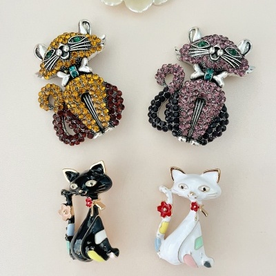 Broches de gato em strass e esmalte sobre fundo claro