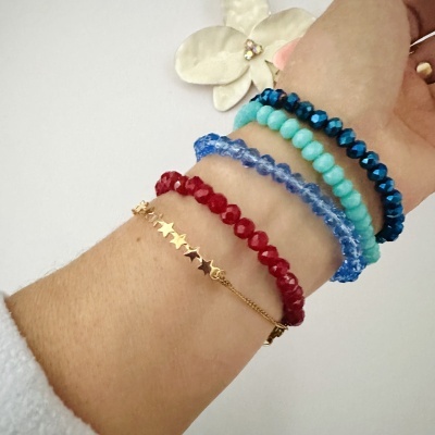 Pulseiras femininas coloridas e dourada com estrelas num pulso