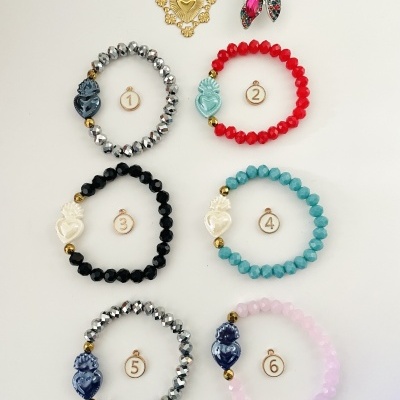 Seis pulseiras coloridas de contas com peças decorativas e dois broches em fundo branco