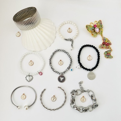 Oito pulseiras variadas e alfinete de borboleta colorido sobre fundo branco