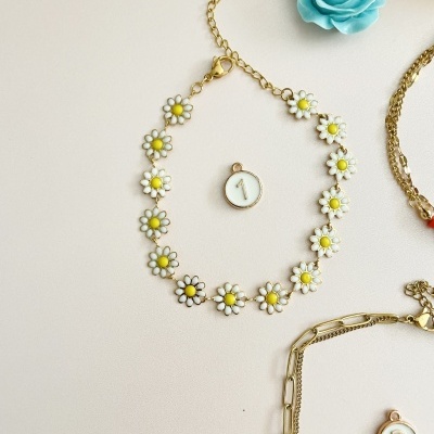 Pulseira flor branca e amarela com contas numeradas e correntes douradas