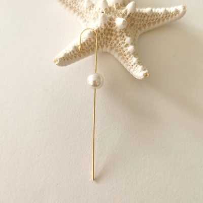 Brinco dourado com pérola pendurado numa estrela-do-mar branca