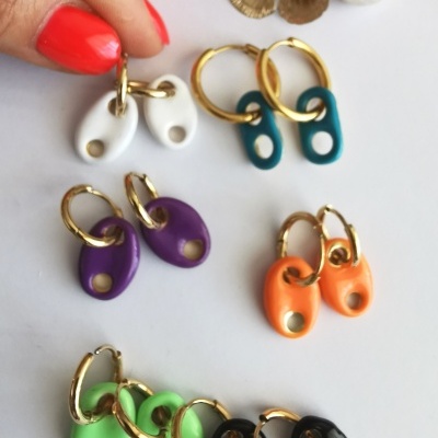 Brincos coloridos de argola dourada com pendentes ovais em silicone sobre fundo branco