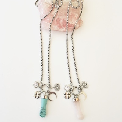 Dois colares com pingentes em forma de mão sobre pedra rosa maior