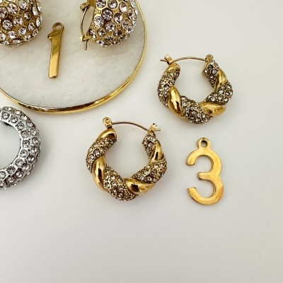 Brincos decorados com pedras brilhantes e números metálicos dourados e prateados