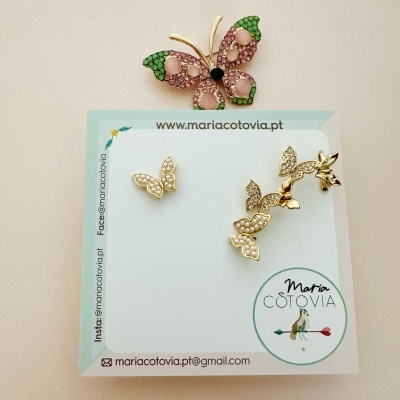 Brincos de borboleta dourados com pérolas sobre cartão de apresentação.