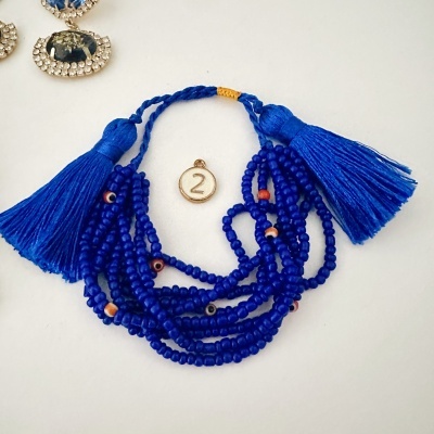 Bracelete de contas azuis com tasséis e peça com número 2