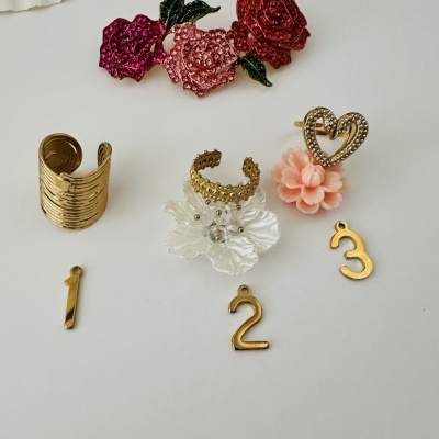 Conjunto de anéis e pendentes dourados com flores coloridas e números