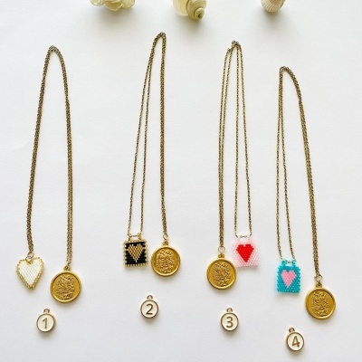 Quatro colares dourados com pendentes redondos e contas coloridas, conchas decorativas sobre fundo branco