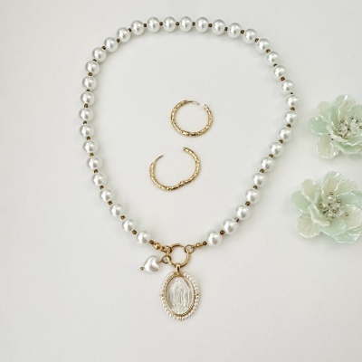 Colar de contas peroladas com pendente oval dourado, dois brincos argola dourados e duas flores decorativas verdes.