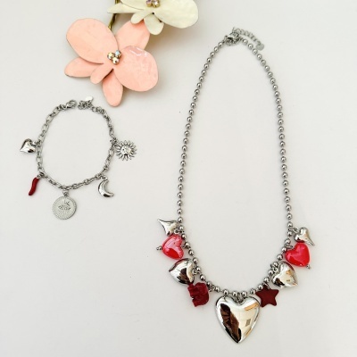 Colar e pulseira prateados com pendentes vermelhos e prateados sobre fundo branco com flores decorativas