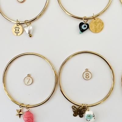 Quatro pulseiras de aro dourado com pendentes variados numeradas