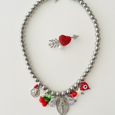 Colar metálico prateado com pendentes coloridos e broche coração vermelho com flecha.