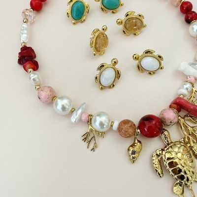 Colar e brincos com design de tartaruga em metal dourado, pedras coloridas e pérolas