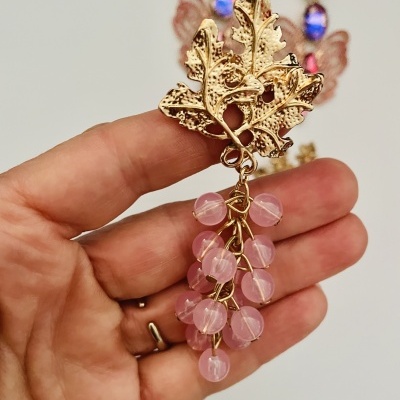 Brinco com folha dourada e conta rosa em fundo neutro