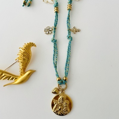 Colar azul com pendente dourado e alfinete de peito dourado em forma de pássaro