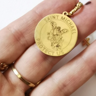 Medalha dourada redonda com gravura de São Miguel e texto em inglês.