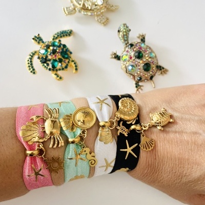 Pulseiras coloridas com pingentes dourados e broches de tartaruga decorativos