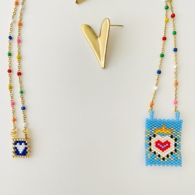 Colares de miçangas coloridas com pendentes e brincos dourados em forma de V sobre fundo branco