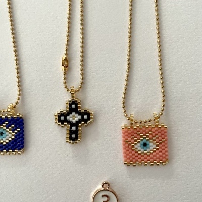 Colares com pingentes de miçangas coloridas pendurados em correntes douradas e medalhão com número 3