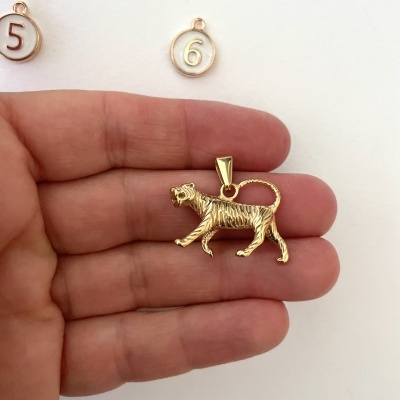 Pingente dourado em forma de tigre com medalhões numerados ao fundo