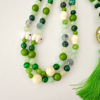 Colar de contas coloridas com elefantes esculpidos e franjas verdes.