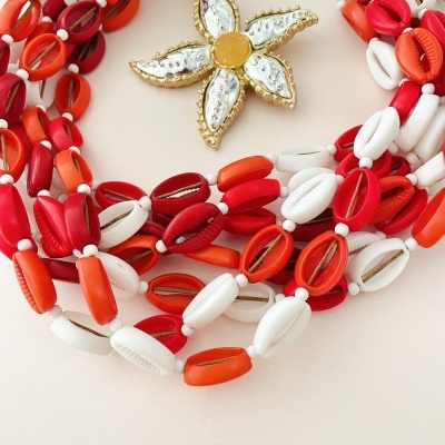 Colar com conchas vermelhas, laranja e brancas e pendente floral com detalhes dourados
