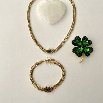 Conjunto de joias com colar, pulseira dourados, coração branco e broche verde em forma de trevo