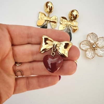 Brincos com laços dourados e pendentes em formas de coração e gota