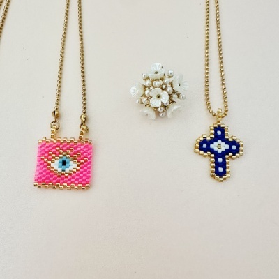 Colares com pingentes em miçangas coloridas e anel floral branco sobre fundo branco