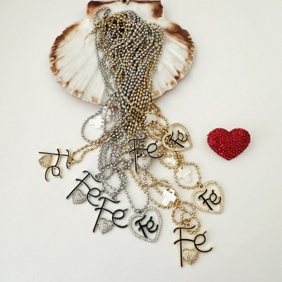 Colares com pendentes de coração e a palavra Fé sobre concha e coração vermelho.