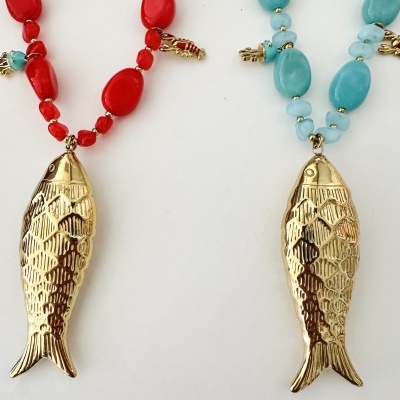 Duas pulseiras coloridas com pendentes em forma de peixe e lagosta dourados