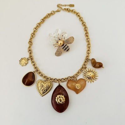 Colar dourado com pendentes castanhos e broche abelha com asas brancas