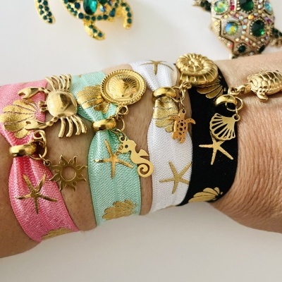 Pulseiras de tecido com pendentes dourados de figuras marinhas em braço
