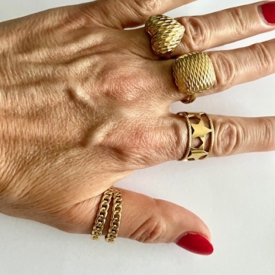 Mão com quatro anéis dourados e unhas vermelhas