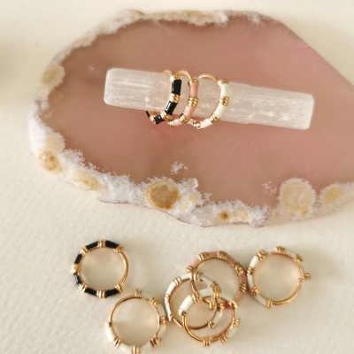 Anéis dourados com detalhes em preto e branco numa base de cristal e ágata rosa.