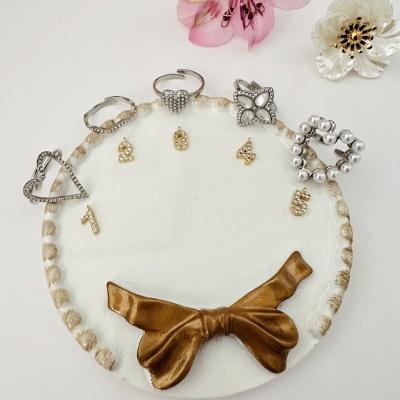 Conjunto de cinco anéis em prata com base decorativa branca e dourada e flores ao fundo