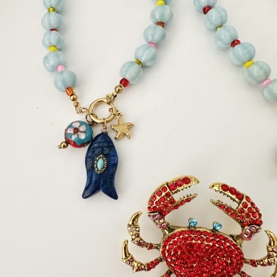 Colar com contas azuis e pérolas coloridas com pingentes marítimos e brincos de caranguejo com strass vermelhos