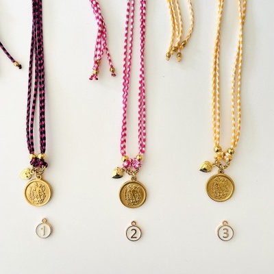 Três colares com medalhões dourados e cordões coloridos numerados de 1 a 3