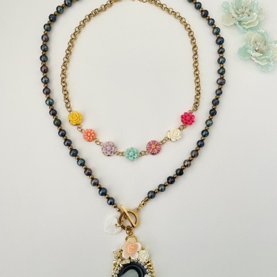 Duas colares com contas e flores coloridas e pingente decorativo sobre fundo branco