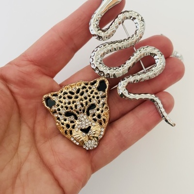 Broche de cabeça de leopardo dourada e cobra prateada em mão