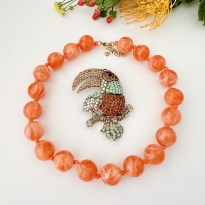 Colar com contas laranja e pendente de pássaro com pedras brilhantes