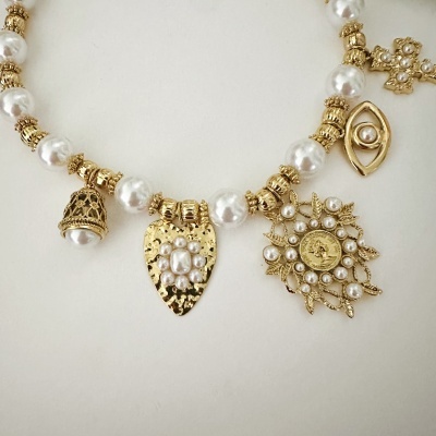 Colar dourado com pérolas e pendentes decorativos em fundo branco