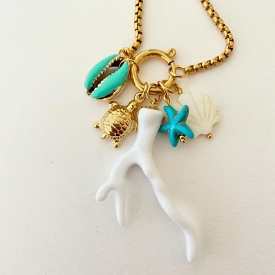 Colar dourado com pendentes marinhos coloridos sob fundo claro