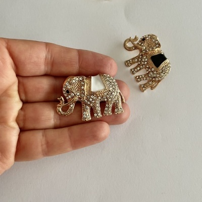 Broches de elefante em metal dourado com pedras brilhantes e detalhes em preto e branco